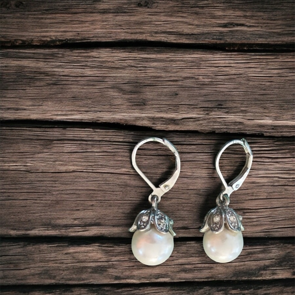 Silver dangle pearl drop earrings with silver detailing at the top.